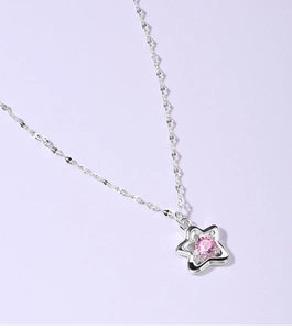 Macro shot of silver star necklace pendant featuring a central pink zircon gemstone