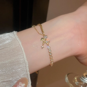 Detail of 18k gold plated bracelet with sparkling butterfly and star charms on wrist