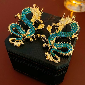 Dettaglio degli orecchini a forma di drago placcati in oro con strass verde smeraldo