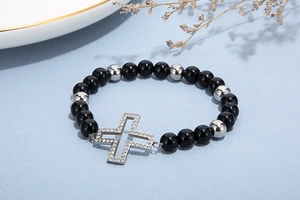 Detail of beaded bracelet with black beads and silver cross pendant with rhinestones