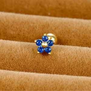 Detailed close-up of blue zircon flower crown ear stud with golden screw ball back
