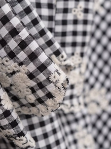 Détail macro du tissu à carreaux noir et blanc avec broderie florale délicate sur le vêtement