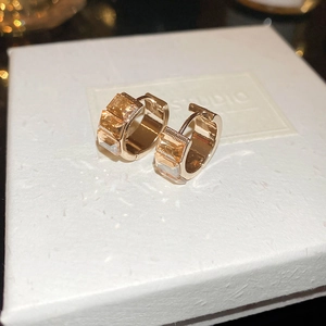 Macro shot of rose gold hoop earrings with champagne rectangular zirconias on jewelry box