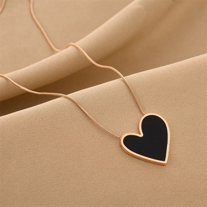 Macro shot of asymmetric heart pendant with black enamel finish and 18K gold plating