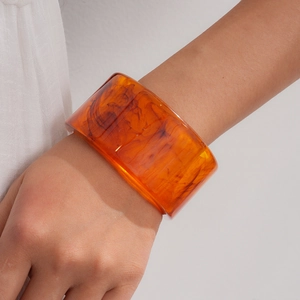 Close-up of stylish amber orange acrylic resin bracelet with marbled swirl pattern
