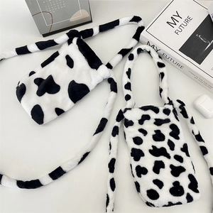 Flat lay of cow print plush water bottle bags with crossbody strap and handles