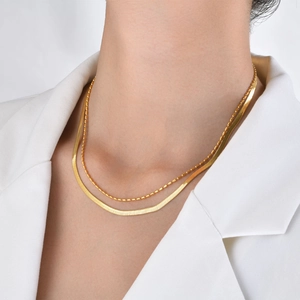 Detail of 18k gold plated double layered necklace featuring snake and bead chains on model