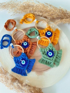 Detail of four colorful macrame evil eye keychains in yellow, orange, blue, and green colors