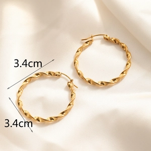 Detail showing 3.4cm diameter of twisted golden hoop earrings on silk background