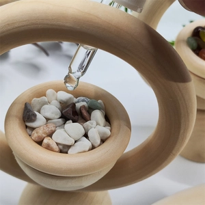 Close-up of essential oil dropper on wooden diffuser with colorful crystal stones