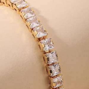 Detail of 18K gold-plated tennis bracelet with square-cut zircon stones in four-prong setting