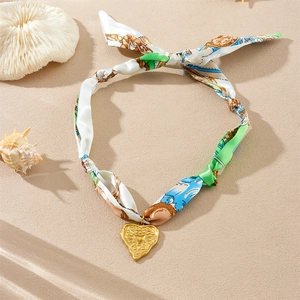 Détail du pendentif cœur doré sur collier ruban de soie avec décor de plage marin