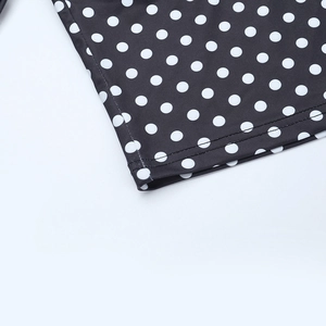 Détail de pois blancs sur tissu noir avec des coutures à double aiguille de haute qualité