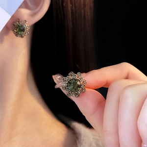 Close-up of vintage flower earrings with dark green gemstone and champagne rhinestones