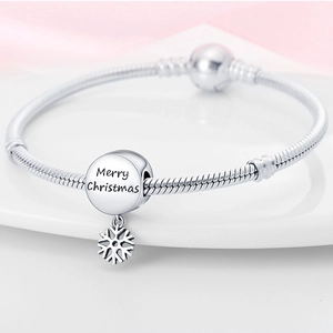 Macro shot of a silver snake chain bracelet with a detailed Christmas snowflake charm