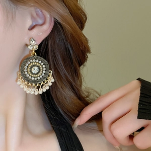 Close-up of ethnic style drop earrings with rhinestones and pearl tassels on a model