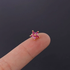 Macro shot of 20G stainless steel stud featuring a pink zircon daisy flower on fingertip