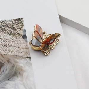 Close-up of vintage double-layer enamel butterfly hair claw with amber resin finish