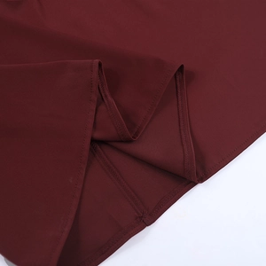 Detail shot of the hemline stitching on a burgundy satin halter backless evening dress