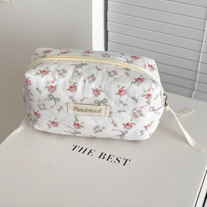 Close-up of a white floral makeup bag with pink rose patterns and quilted fabric texture