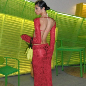 Detail of sexy red backless knit maxi dress with long sleeves in a modern green room