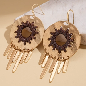 Detail of gold metal earrings featuring woven dark brown cord and long flat tassel fringe