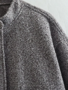 Close-up of grey sherpa fleece texture showing curly fiber details and premium stitching