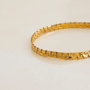 Close-up of vintage gold stainless steel flat chain bracelet with textured metal links