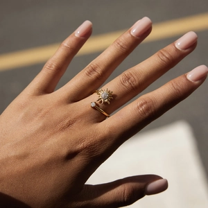 Elegant gold sunburst zircon ring in stainless steel worn by a model in natural light