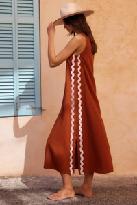 Detail of rust red sleeveless dress with white wavy lace trim and linen texture