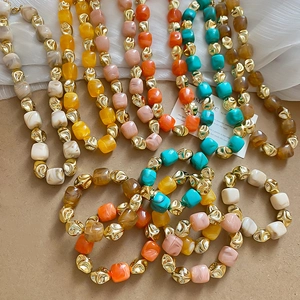 Flat lay of colorful acrylic beaded bracelets with resin and textured metal accents