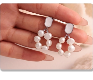Macro detail of ferris wheel earrings with white freshwater pearls on silver studs