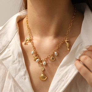 Close-up of gold ocean theme necklace with starfish and shell charms on a white shirt