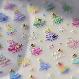 Macro shot of 3D Christmas nail stickers with colorful trees and gold bead accents