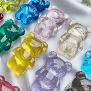 Dettaglio di vari supporti per telefono in resina a forma di orsetto colorati e glitter