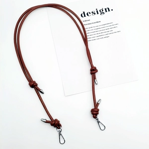 Detail of adjustable brown leather shoulder strap with silver metal buckle on white surface