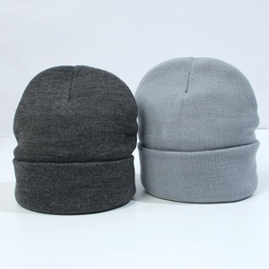 Detailed flat lay of dark and light grey knitted beanies with soft ribbed texture