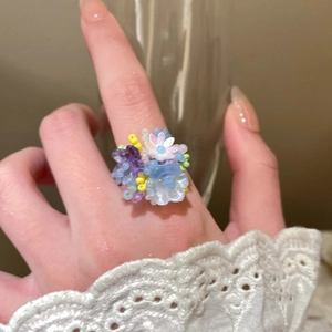 Detailed close-up of handmade colorful bead flower ring worn on a finger