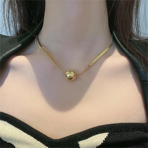 Close-up of double-layered gold ball pendant necklace with snake and bead chains
