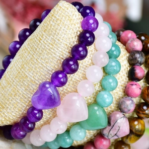 Macro shot of natural amethyst stone beaded bracelets with heart charms on linen stand