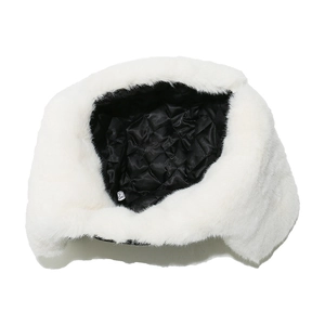 Detail of white faux fur trapper hat featuring black quilted lining and ear flaps