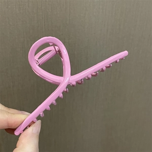 Primer plano de una pinza de pelo de metal rosa con acabado suave y diseño trenzado