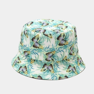Détail d'un chapeau bob blanc avec motifs de papillons colorés et de feuilles vertes