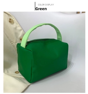 Detail of green square handbag featuring textured light green handle and smooth PU surface