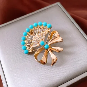 Vintage gold fan-shaped brooch with turquoise beads and rhinestones on velvet