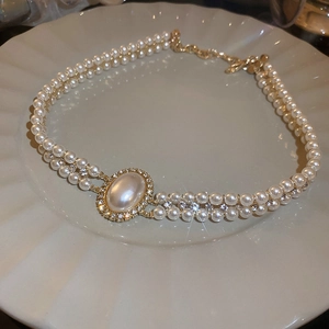 Détail d'un collier de perles à deux rangs avec un pendentif ovale doré vintage