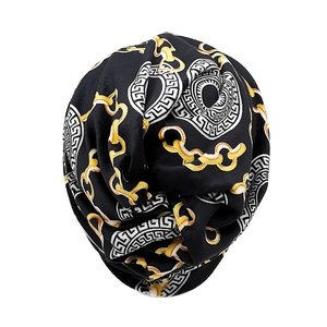 Detail of black beanie featuring gold chain print and Greek fret pattern with rich texture