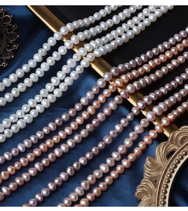 Detailed view of natural white, peach, and purple freshwater pearls on dark blue silk
