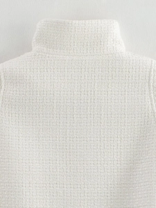 Close-up of white tweed poncho collar showing premium woven texture and fabric detail