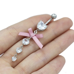 Détail du piercing de nombril avec nœud en soie rose et zircons en forme de cœur